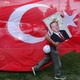 An Erdoğan supporter carries a poster with his face in front of a Turkish flag.