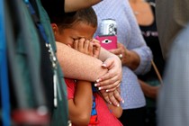 A young boy cries in a woman's embrace at a prayer vigil following the mass shooting in Las Vegas. 