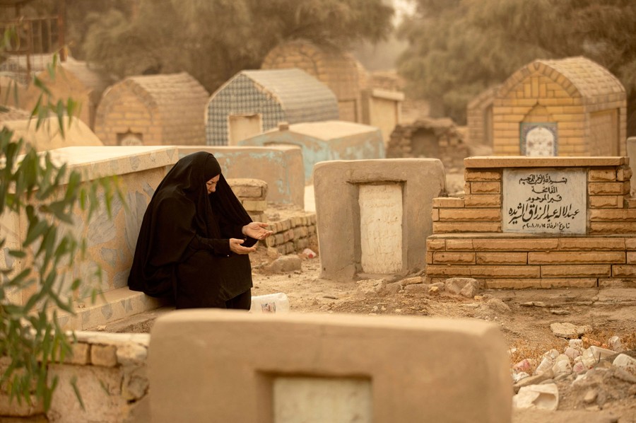 A woman says prayers among headstones in a cemetery.