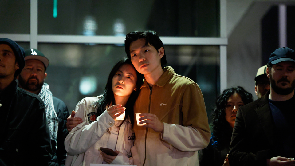 Photograph of a man and woman holding candles in a crowd at a vigil