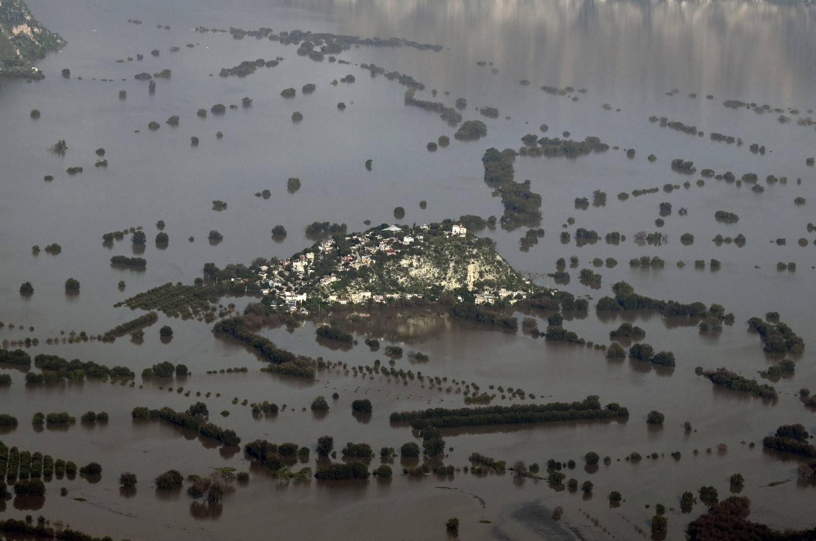 An aerial view of a flooded town on a hill surrounded by water