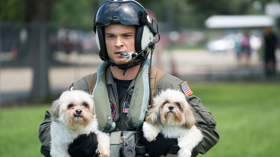 A Naval Aircrewman carrying two dogs.