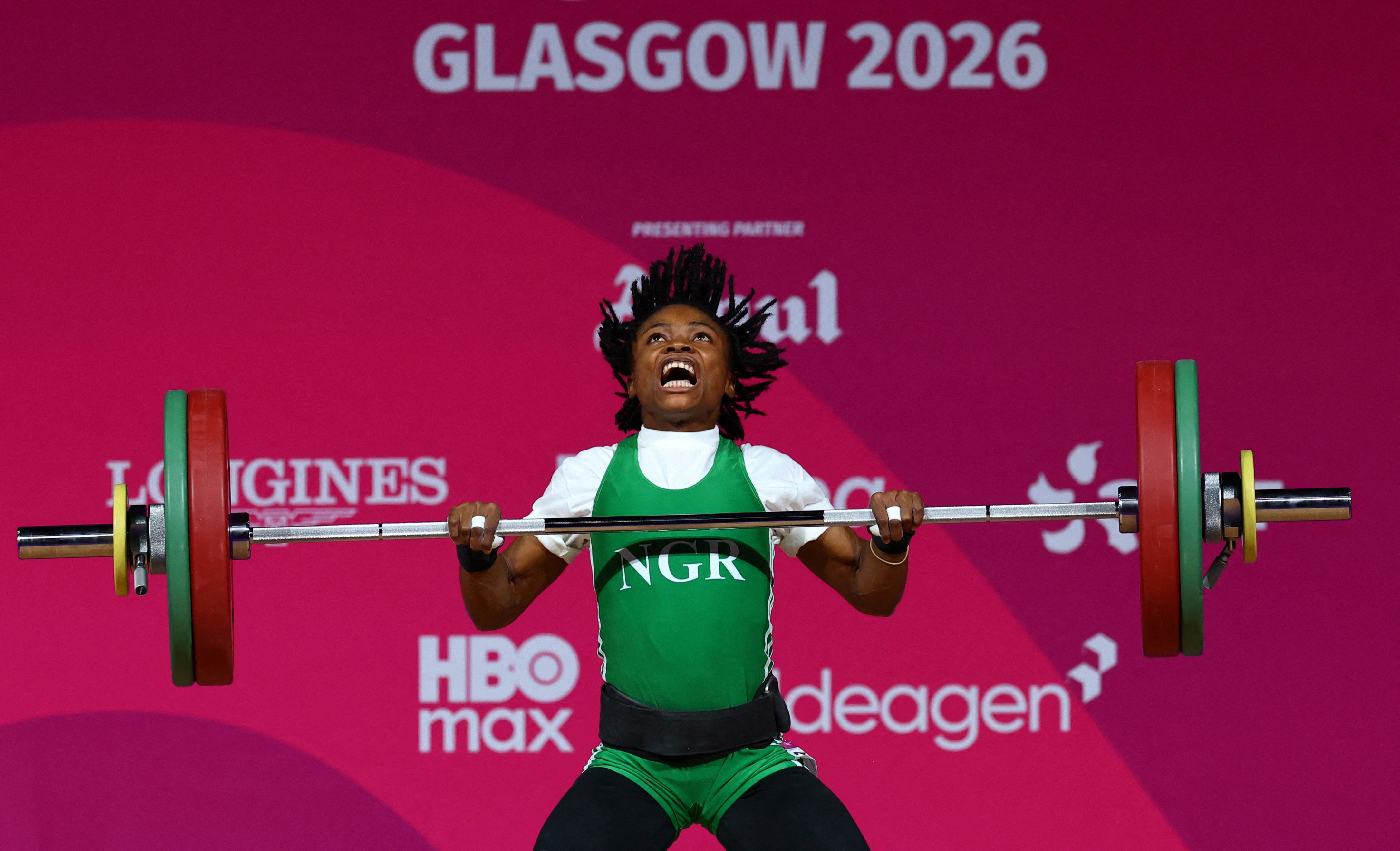 A weightlifter with an expression of effort on their face, during a lift in competition