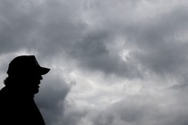 The silhouette of Donald Trump in front of a grey cloudy sky