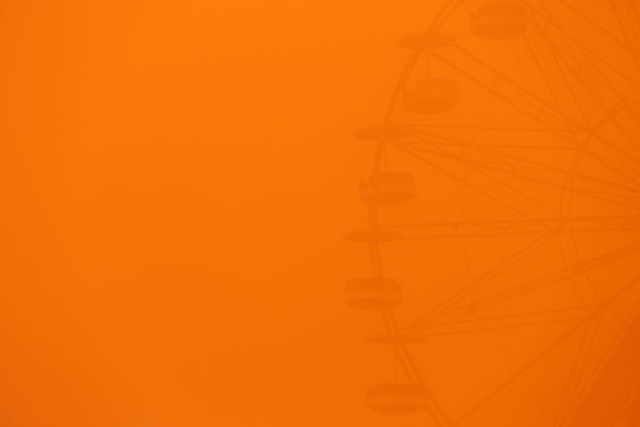 A Ferris wheel is barely visible through a thick haze of dust.