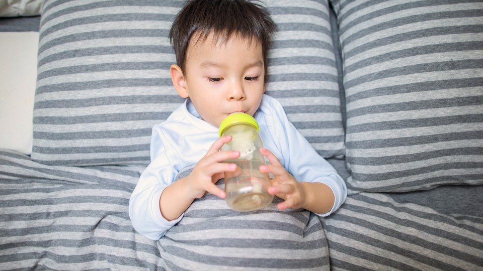 A toddler drinks from a bottle.