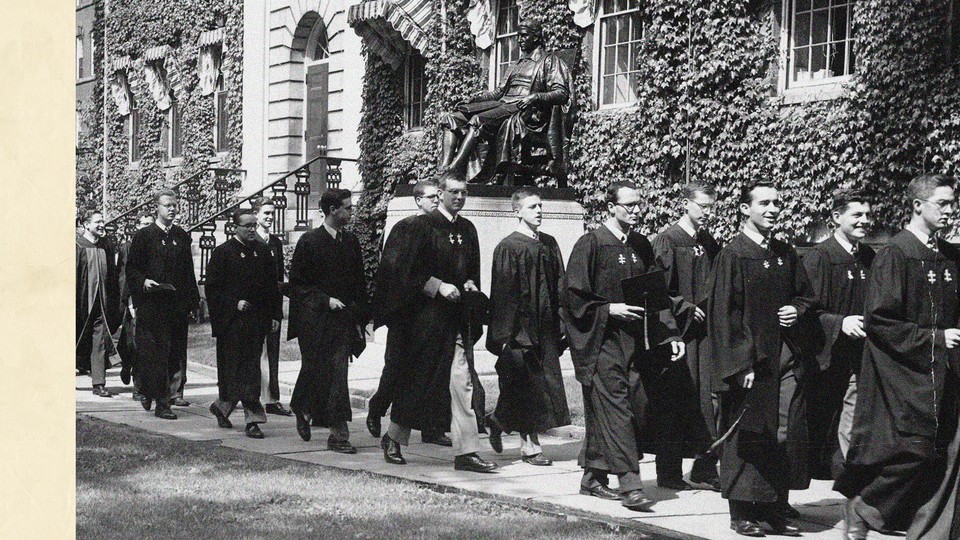 A black and white photograph of male Harvard students from the 1950s in graduation robes processing past an ivy-lined building and the John Harvard statue