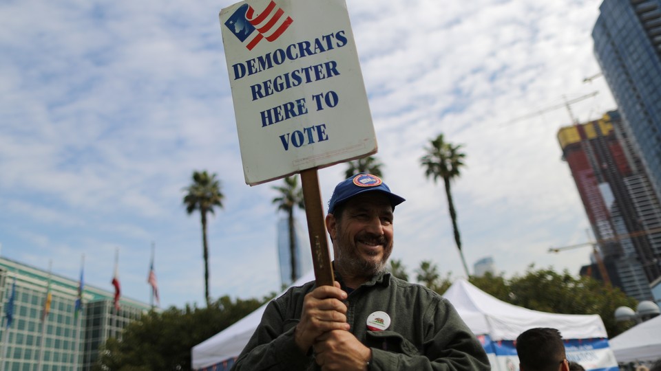 A Democratic Party worker holds up a "register to vote" sign.