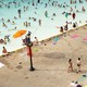 Photograph of people swimming, wading, and relaxing at a public pool