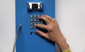 A photograph of a hand dialing on a landline phone