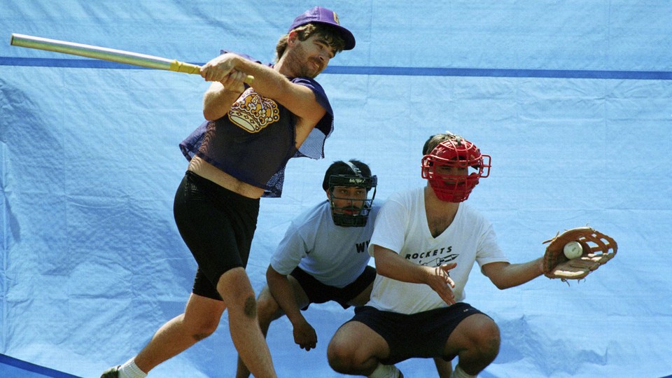 A player at bat strikes out while a Wiffle ball rests in the catcher's mitt.