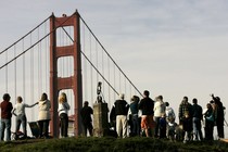 People gather on a hill in view of the Golden Gate Bridge