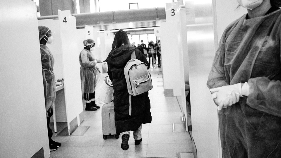 Photo of an air passenger from China walking through the COVID-19 testing booths at the Paris-Charles-de-Gaulle airport