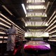 A worker rides a lift past stacks of vertical farming beds with LED lights