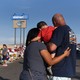 A man, woman, and child visit an impromptu memorial in El Paso.