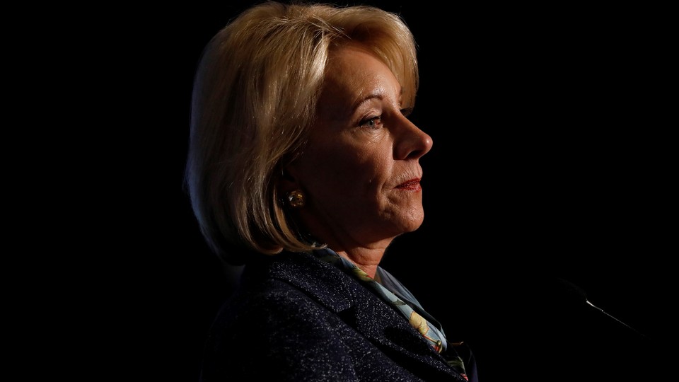 Betsy DeVos speaking at podium against a black background