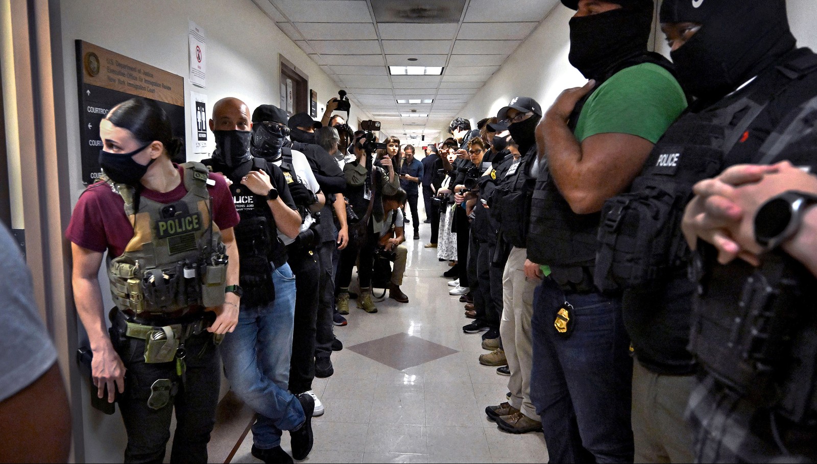 Many masked federal officers wait in a hallway outside courtrooms.
