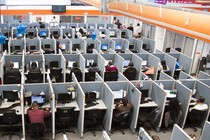 Workers sit at desks in a call center