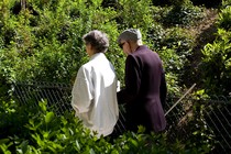 Photo of two people walking arm-in-arm in a park