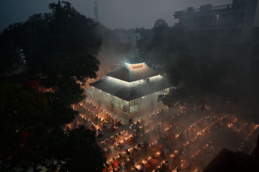 An elevated view of hundreds of people praying outside a temple at night