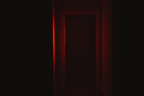 Front view of a door illuminated with red lighting in dark corridor.