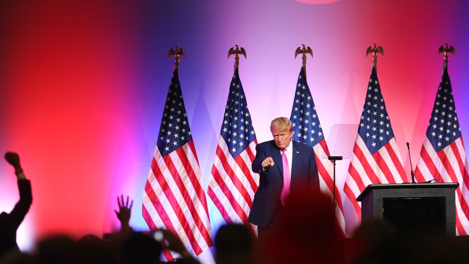 Trump stands near a podium and points at the crowd in front of him