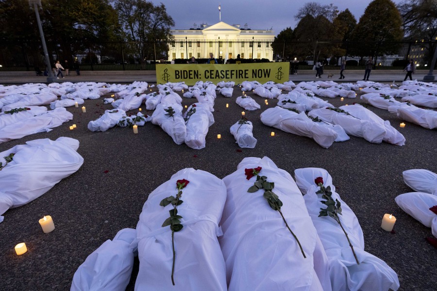 A banner reading "Biden: Ceasefire Now," along with many fake white body bags, displayed in front of the White House