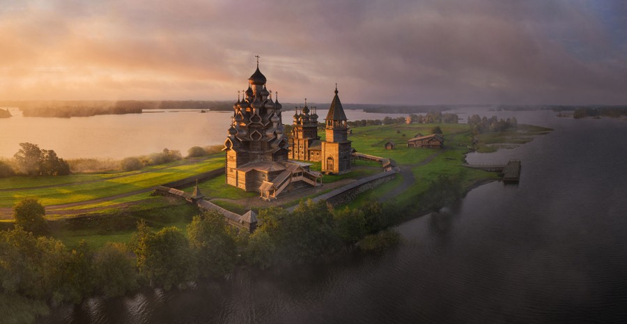 An aerial view of a narrow island on which sit several historical wooden structures, including an ornate 22-dome Russian Orthodox church
