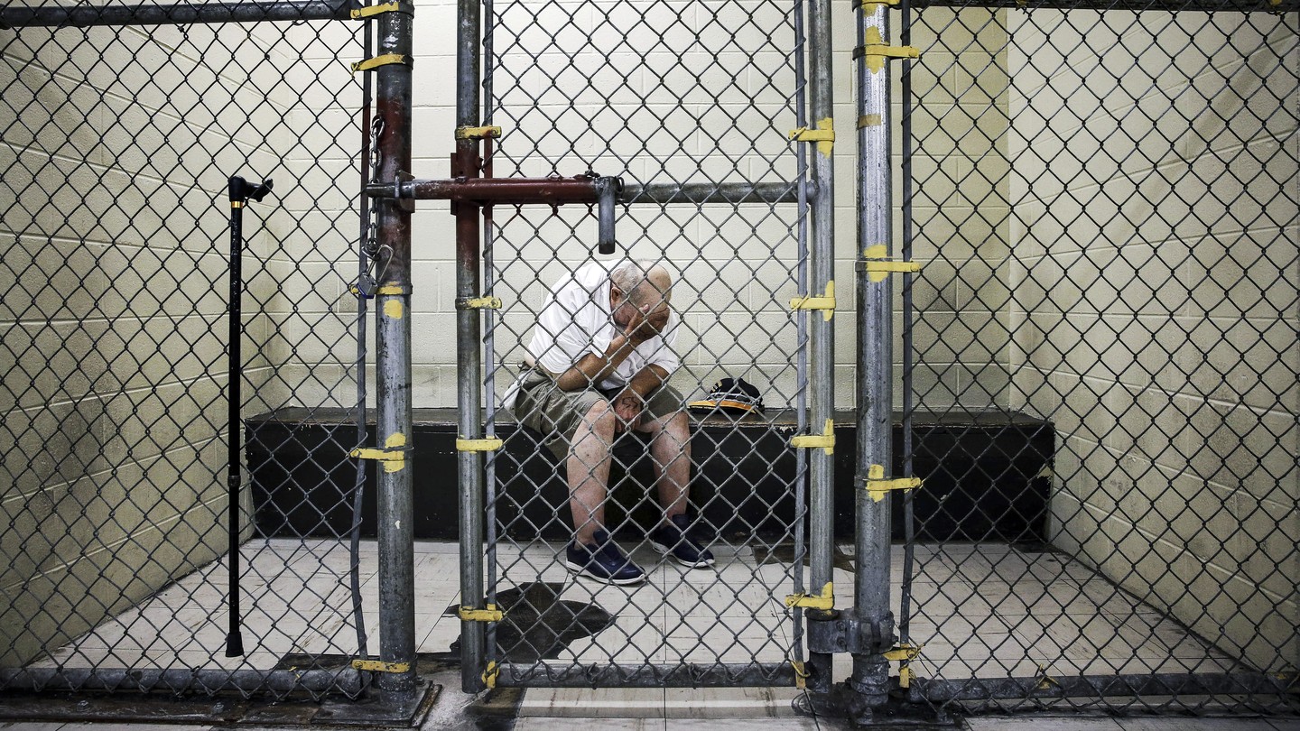 A man in a jail cell with his head in his hands