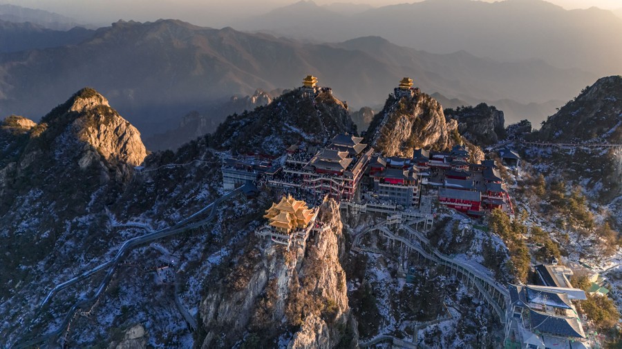 An aerial view of palace-like structures atop a rocky mountain