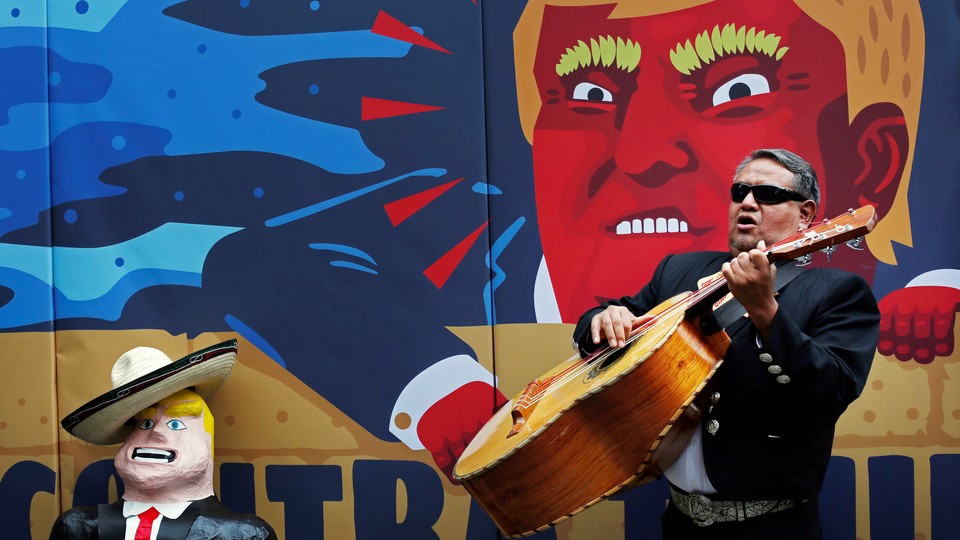A member of the mariachi plays music next to a pinata depicting U.S. Republican presidential nominee Donald Trump in front of a wall with a caricature of him during a campaign encouraging U.S. citizens in Mexico to register to vote against Trump, in Mexico City, Mexico September 25, 2016.
