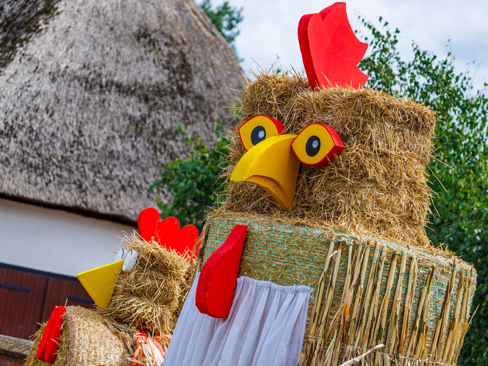 Two oversized chickens made from straw bales advertise a harvest festival.