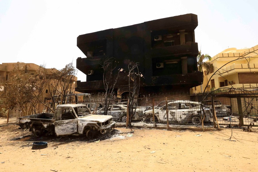 Destroyed cars sit next to a blackened building following a battle.