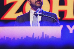 Photograph of Zohran Mamdani speaking at a podium during a campaign event with the top of his head cropped out of frame