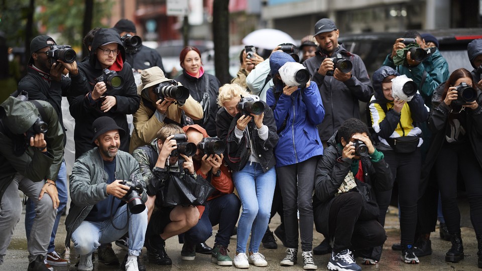 A crowd of paparazzi on the sidewalk