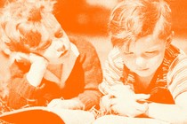 Two kids read a book together in the grass