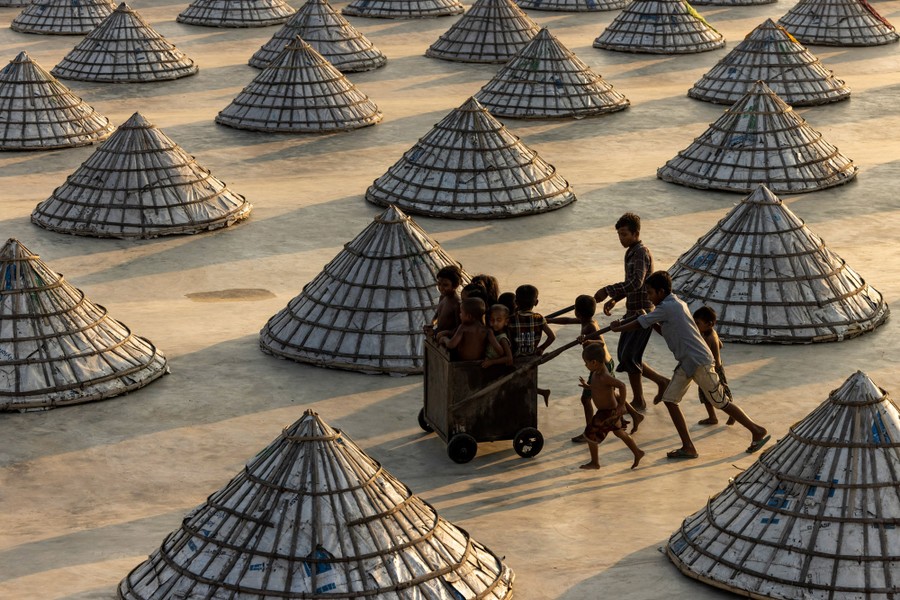 Several children play with a cart, weaving in and out of scores of giant cones