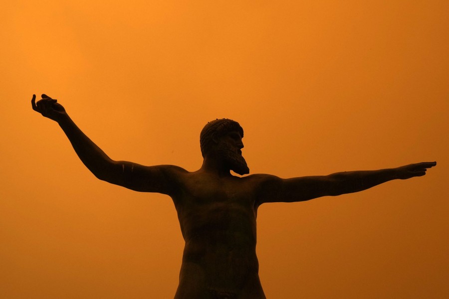 A state of Poseidon stands under a smoky red sky.