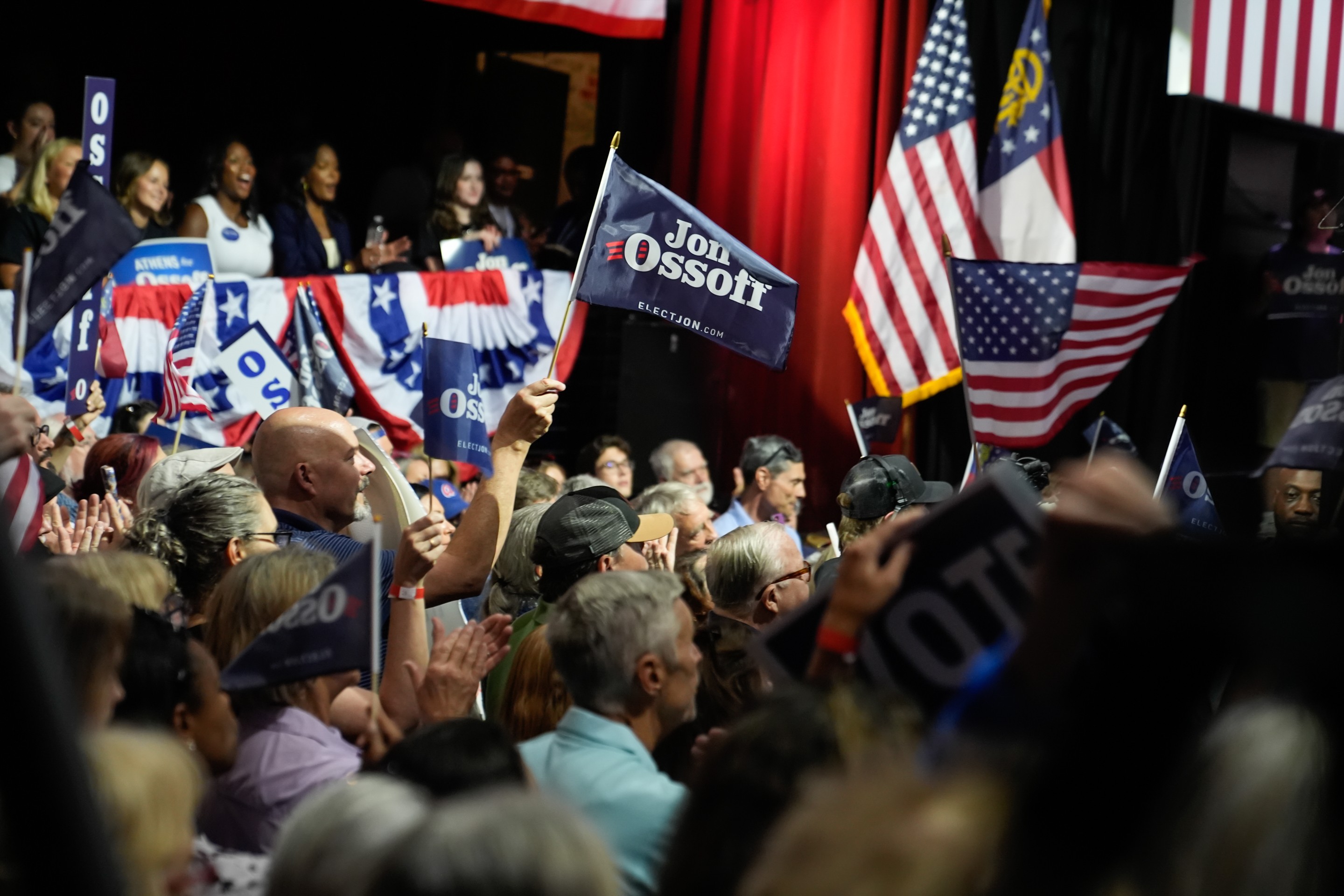 a person holds a Jon Ossoff flag in a crowd