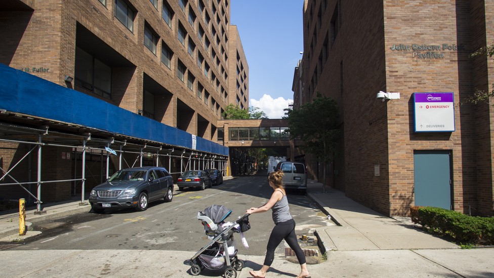 A young woman pushes a stroller past Long Island College Hospital in Brooklyn, New York.