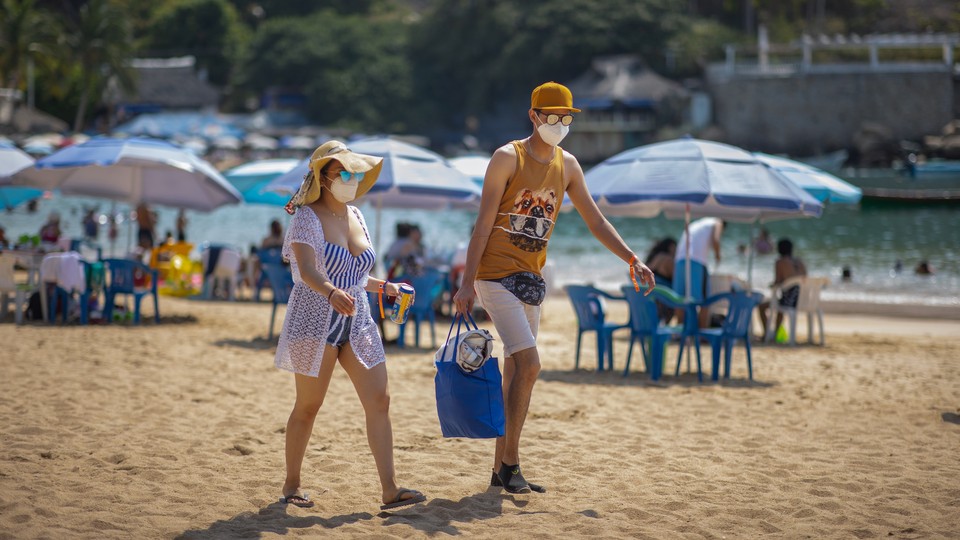 Tourists wearing face masks on a beach in Mexico