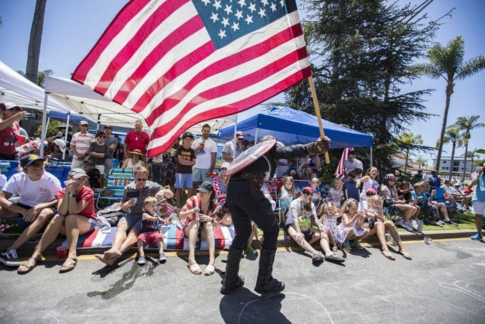 Captain America cosplayer holding an American flag during a parade