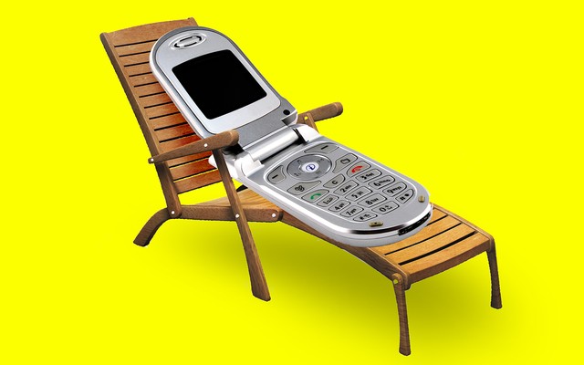 A flip phone lying on a deck chair (like a person).