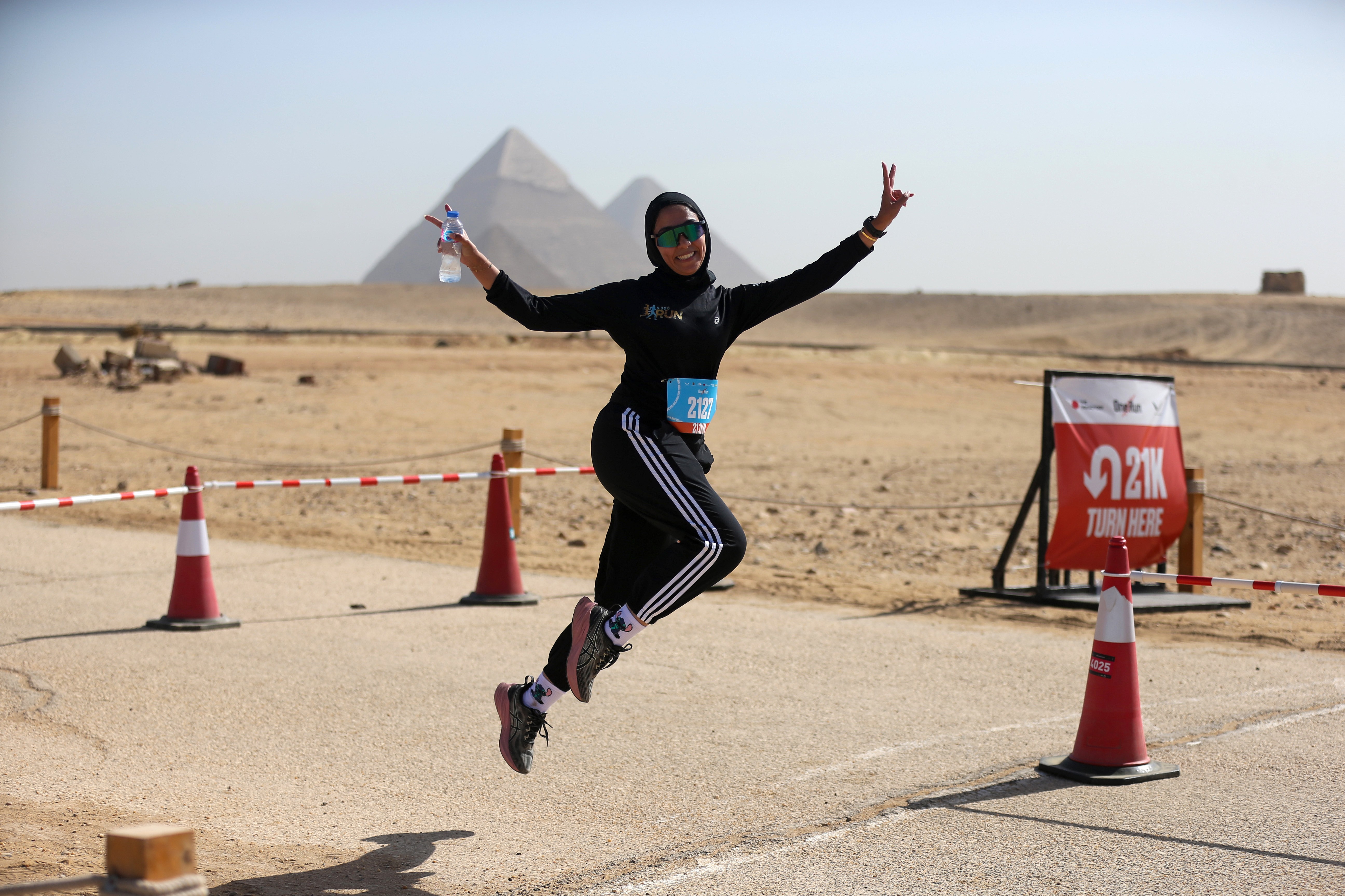 A runner jumps and poses in front of the pyramids in Giza.
