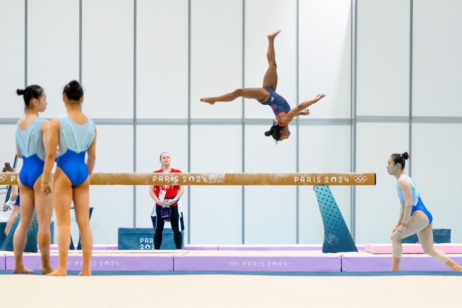 Several gymnasts practice on various equipment.