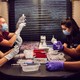 Four people sit filling vials with vaccine using syringes.