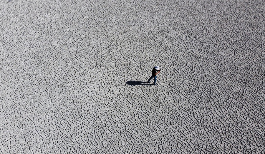 A man stands on a dry, cracked lake bed.