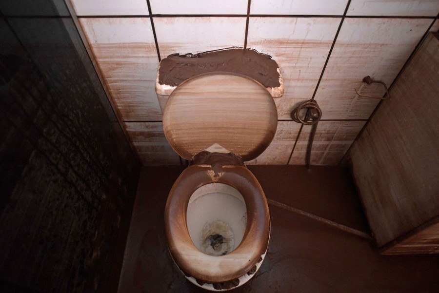 A muddy bathroom is seen, with lines of mud left striping the lower walls.