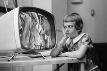 A vintage photo of a young girl staring at a TV screen