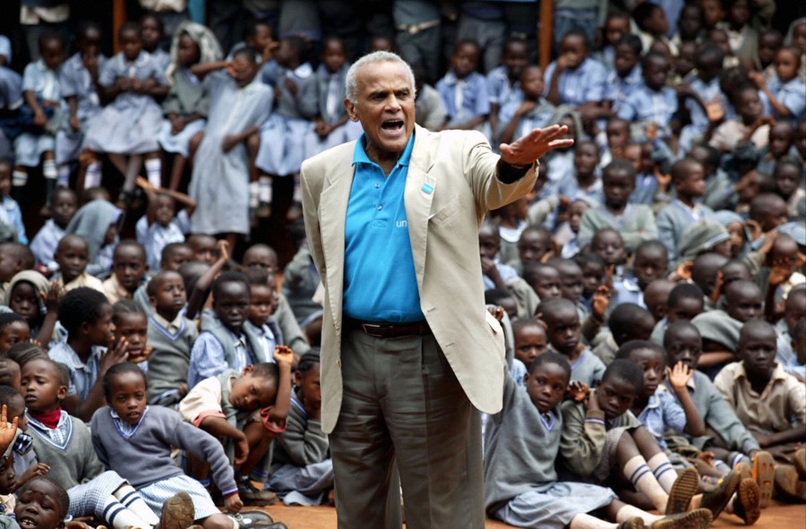 Harry Belafonte speaks in front of a crowd of schoolchildren.